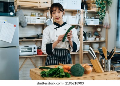 Portrait Asian Female Cook Is Showing And Giving Tips Of How To Selecting Fresh Vegetables While Filming An Online Cooking Videos In A Rustic Kitchen.