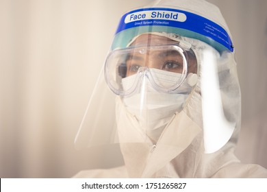 Portrait Of Asian Female Doctor Wearing Face Shield And PPE Suit For Treatment Coronavirus Patients.