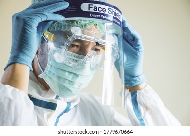 Portrait Of Asian Female Doctor Wearing Face Shield And PPE Suit For Treatment Coronavirus Patients.