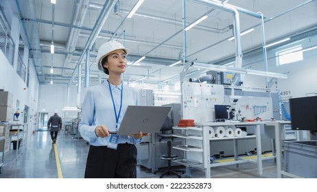 Portrait of an Asian Female Engineer in Hard Hat Standing and Using Laptop Computer at Electronic Manufacturing Factory. Technician Thinking About Daily Tasks and Working on Development Data. - Powered by Shutterstock