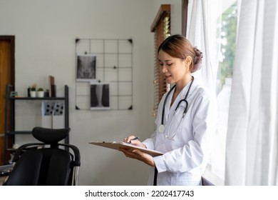 Portrait Asian Female Medical Doctor Taking Note On Clipboard At Her Office.