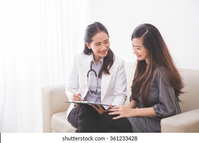 A Portrait Of An Asian Female Patient Consulting With A Female Doctor