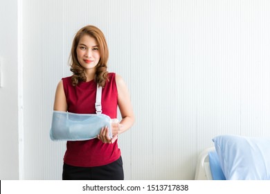 Portrait of asian female patient in red dress broken arm after accident and wear arm splint for treatment and bed in the room hospital background,copy space - Powered by Shutterstock