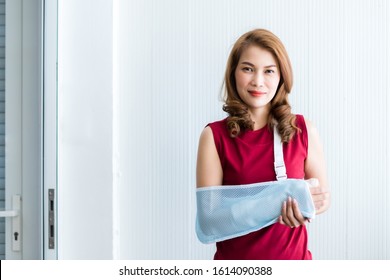 Portrait Of Asian Female Patient In Red Dress Broken Arm After Accident And Wear Arm Splint For Treatment And Bed In The Room Hospital Background,copy Space