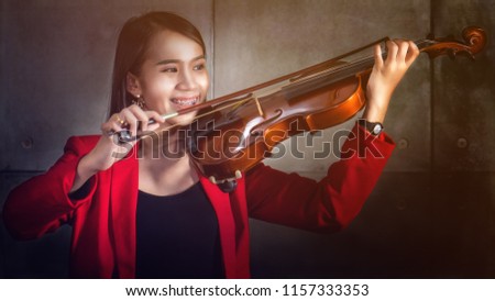 portrait of Asian female in red shirt plaing violin, soft focused with two tone