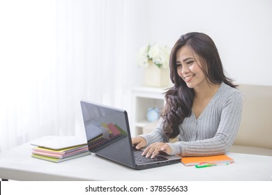 Portrait Of Asian Female Student At Home Studying Using Laptop