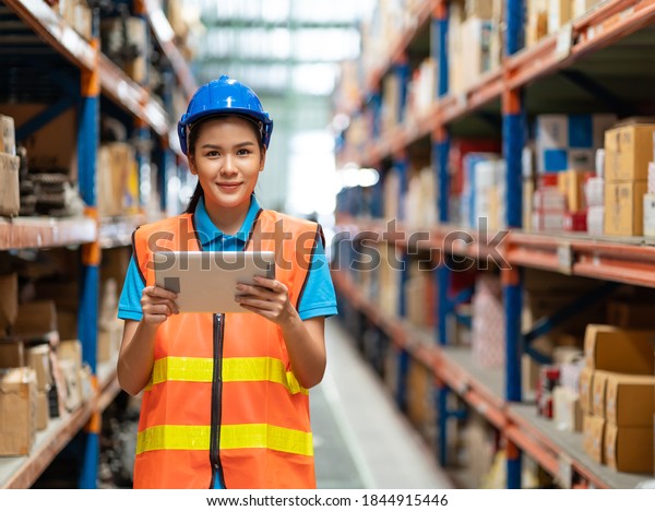 Portrait of Asian female worker with\
tablet pc computer working in automotive spare parts warehouse.\
people, car service, repair and maintenance\
concept