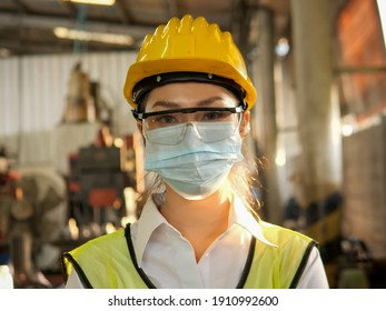 Portrait Asian Female Worker Is Wear Protection Mask Face And Safety Helmet And Wearing Suit Green Reflective At Factory. For Working Industrial Due To Covid Pandemic Crisis Concept.