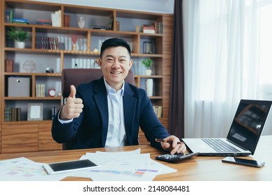 Portrait Of Asian Financier, Businessman Working In Office, Paperwork, Looking At Camera And Smiling, Showing Thumbs Up