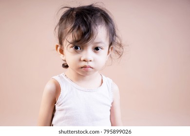 Portrait Of An Asian Girl With A Messy Hair Wearing White Sleeveless Top On A Brown Background. Bad Hair Day Concept.