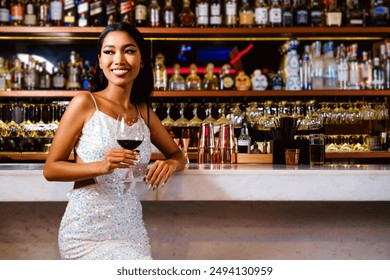 Portrait of an Asian glamour, wearing a white glitter dress smiling and drinking a glass of wine at a luxury nightclub counter bar with liquor in the background. Attractive woman enjoy and fun hangout - Powered by Shutterstock