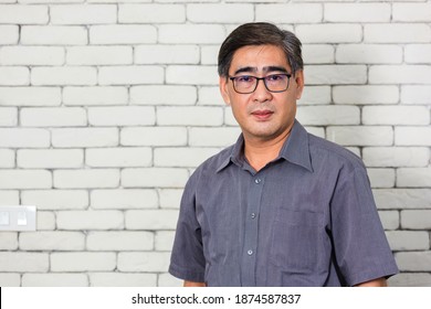 Portrait Of Asian Handsome Senior Elderly Man Wear Eyeglasses On White Brick Wall Background. Old Man Standing Golden Age Grandfather Healthcare Cheerful Lifestyle