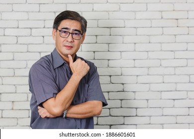 Portrait Of Asian Handsome Senior Elderly Man Wear Eyeglasses On White Brick Wall Background. Old Man Standing Golden Age Grandfather Healthcare Cheerful Lifestyle