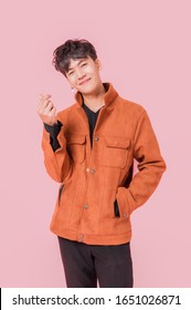 Portrait of asian handsome young man in fashionable clothing and standing posing mini heart with smiling and happiness isolated on pink background.