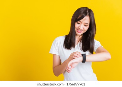 Portrait Asian of a happy beautiful young woman smiling looking and pointing finger her smart wristwatch studio shot isolated on yellow background - Powered by Shutterstock