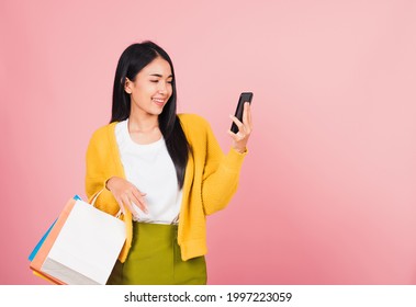 Portrait Asian Happy Beautiful Young Woman Teen Shopper Smiling Standing Excited Holding Online Shopping Bags Online Colorful Multicolor And Smartphone On Hand, Studio Shot Isolated On Pink Background