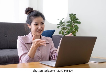 Portrait Asian Of Happy Beautiful Young Woman Work From Home She Sitting On Sofa Raise Hand And Say Hello On Laptop Computer In House Living Room Studio