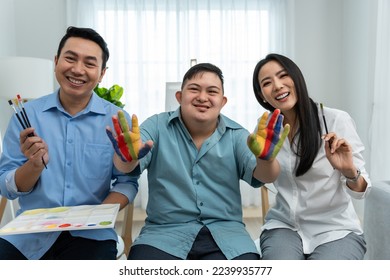 Portrait Asian happy family  parents draw picture and young son  Beautiful loving couple  mother   father take care   teach young man painting artwork indoors   looking at camera in house 