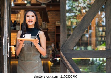 Portrait of a Asian Happy woman Standing In Front of his Coffee Shop hand serving present wooden tray with Cup of Coffee small business welcome reopen again,asian female smiling barista holding coffee - Powered by Shutterstock