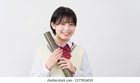 Portrait of Asian high school student smiling with the diploma in a tube in white background