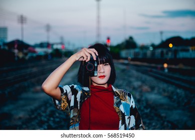 Portrait of asian hipster girl on sunset at railway vintage style,Grain and noise has been added to make effect of photographic film. - Shutterstock ID 568519450