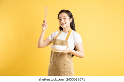 Portrait of Asian housewife girl posing on yellow background - Powered by Shutterstock