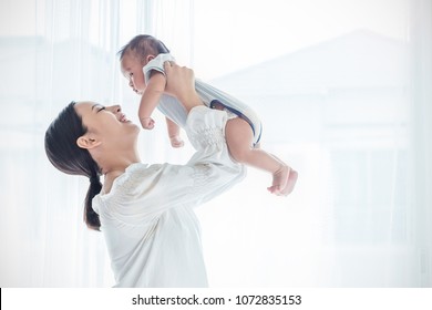Portrait of asian Indian or caucasian mother lifting and playing with newborn baby, baby talking to mother day. Health care family love together. Asian girl lifestyle. Asia mother's day concept 