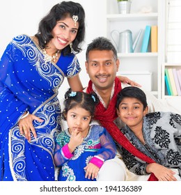 Portrait Of Asian Indian Family At Home, Happy Parents And Children In Traditional Sari.