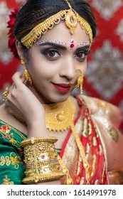 Portrait Of Asian/ Indian Female Model In Beautiful Bridal Makeup With Heavy Gold Jewellery . Close Up Of Lipstick And Eye Makeup On Indian Model.