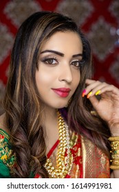 Portrait Of Asian/ Indian Female Model In Beautiful Bridal Makeup With Heavy Gold Jewellery . Close Up Of Lipstick And Eye Makeup On Indian Model.