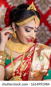 Portrait Of Asian/ Indian Female Model In Beautiful Bridal Makeup With Heavy Gold Jewellery . Close Up Of Lipstick And Eye Makeup On Indian Model.