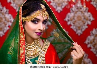 Portrait of Asian/ Indian female model in beautiful bridal makeup with heavy gold Jewellery . Close up of Lipstick and eye makeup on Indian Model.
