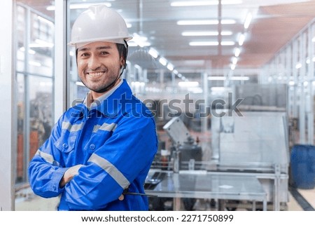 Portrait of Asian Indian manual man worker is standing with confident with blue working suite dress and safety helmet in front orange background. Concept of smart industry worker operating.