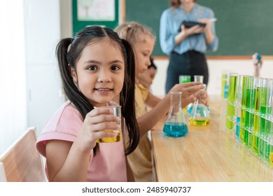 Portrait of Asian kid student learning in classroom at elementary school. Adorable young schoolgirl looking at camera study science and doing chemistry experiment with fun activity at kindergarten. - Powered by Shutterstock