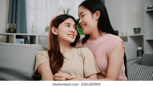 Portrait of Asian lesbian couple sit on the sofa, talk and hug happily, sharing good feelings with each other in the living room at home. LGBTQ Lifestyle. - Powered by Shutterstock