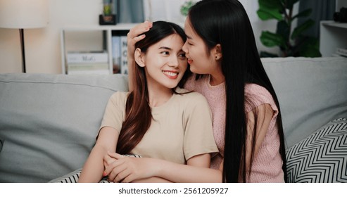 Portrait of Asian lesbian couple sit on the sofa, talk and hug happily, sharing good feelings with each other in the living room at home. LGBTQ Lifestyle. - Powered by Shutterstock