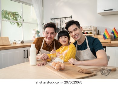 Portrait Of Asian LGBTQ Man Gay Family Teach Girl Kid Baking In Kitchen. Attractive Handsome Male Couple Take Care And Spend Time With Little Cute Child Bake Bakery, Enjoy Parenting Activity At Home.