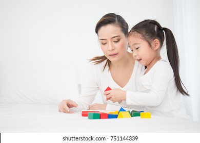 Portrait of asian little cute girl playing colorful blocks with her mother over white background. Learning by playing education home school concept. Mother teaching her daughter to play blocks.