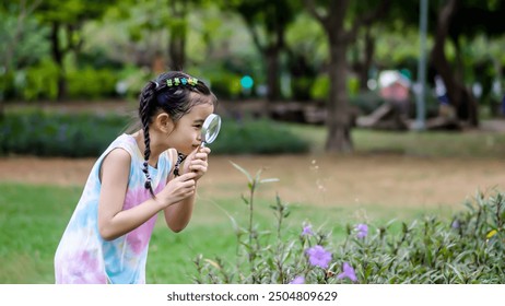 Portrait of asian little girl exploring the nature with magnifying glass outdoors, Child woman playing in the park with magnifying glass. Curious kid exploring nature by magnifier - Powered by Shutterstock