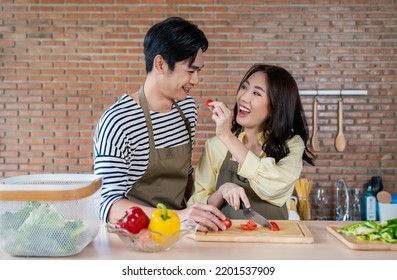 Portrait Of Asian Lovely Couple Cooking Food Chopping Vegetables In The Kitchen. Happy Asian Family, Father Mother, Family’s Day, Together Healthcare Cooking Plant Based Diet Food Concept