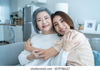 Portrait Of Asian Lovely Family, Young Daughter Hugging Older Mother. Attractive Woman And Senior Elder Mature Mom Sit On Sofa, Enjoy Activity At Home Together In Living Room And Smile, Look At Camera