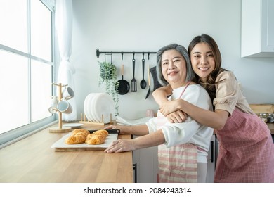 Portrait Of Asian Lovely Family, Young Daughter Stand With Old Mother. Attractive Female And Senior Elderly Mom Wear Apron Enjoy Activity At Home To Bake Croissant In Kitchen And Smile, Look At Camera