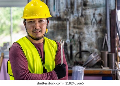 Portrait Of Asian Machinist In Safety Suit Holding The Wrench Over The Stack Of Wrench In Metalworking Factory, Lathe Grinding Metalworking Industry Concept