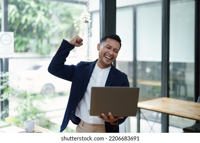 Portrait Of An Asian Male Business Owner Standing With A Computer Showing Happiness After A Successful Investment.