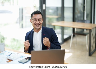 Portrait Of An Asian Male Business Owner Standing With A Computer Showing Happiness After A Successful Investment.