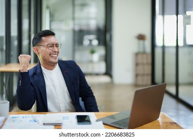 Portrait Of An Asian Male Business Owner Standing With A Computer Showing Happiness After A Successful Investment.