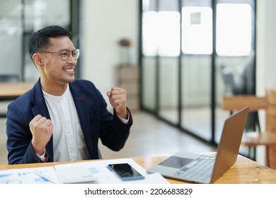 Portrait Of An Asian Male Business Owner Standing With A Computer Showing Happiness After A Successful Investment.