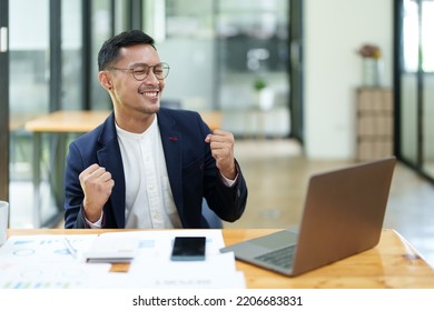 Portrait Of An Asian Male Business Owner Standing With A Computer Showing Happiness After A Successful Investment.