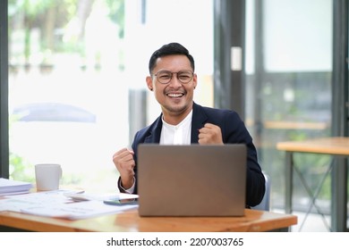 Portrait Of An Asian Male Business Owner Standing With A Computer Showing Happiness After A Successful Investment.
