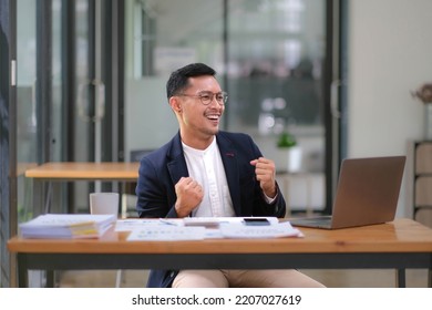 Portrait Of An Asian Male Business Owner Standing With A Computer Showing Happiness After A Successful Investment.
